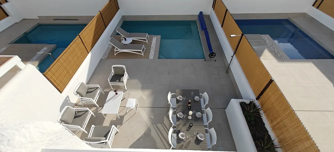 Het hoofdterras met eettafel, loungeset en zwembad van bovenaf